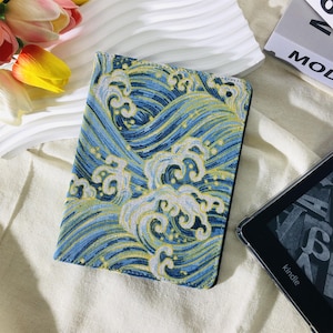May include: A blue and yellow wave pattern Kindle cover. The cover is rectangular and features a repeating design of stylized waves. The cover is on a white surface with a Kindle device visible in the background.