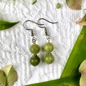 Puede incluir: Un par de pendientes de plata con dos cuentas de jade verde en cada pendiente.