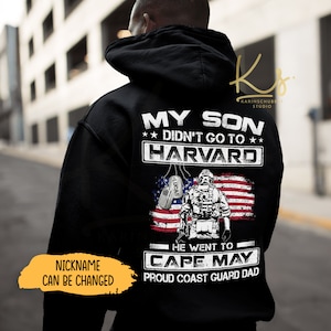 May include: Black hooded sweatshirt with white text that reads "MY SON DIDN'T GO TO HARVARD" above an American flag design and a Coast Guard soldier graphic. Below, it says "HE WENT TO CAPE MAY". Includes a customizable nickname.