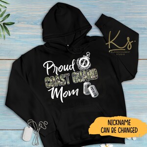 May include: Black hooded sweatshirt with a camouflage print and the text "Proud Coast Guard Mom" with a compass and a dog tag that says "Patrick". The text "Nickname can be changed" is also visible.