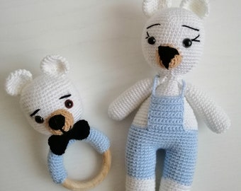 May include: Two handmade crochet bear toys. One is a rattle with a wooden ring and a black bow tie. The other is a larger bear wearing blue overalls. Both bears are white with black eyes and noses.