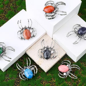 Handcrafted natural crystal spider featuring a polished gemstone body set in a finely crafted alloy spider frame. designed with natural stones creating a luxurious and artistic jewelry piece. The smooth gemstone surface and detailed spider legs give it a striking and elegant appearance. Perfect as a pendant necklace or brooch accessory symbolizing creativity, protection, and good fortune. Ideal for meditation energy healing, spiritual balance, fashion styling, gift giving, and decorative display