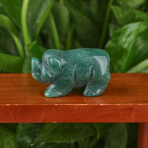 May include: A small, green jade pig figurine. The pig is carved in a standing position with its head turned to the side. The figurine is smooth and polished.