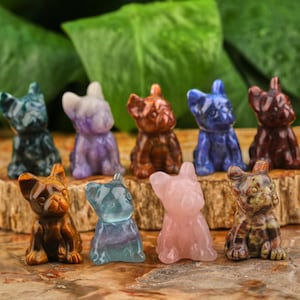 May include: Ten small, carved, crystal dog figurines in various colors, including blue, green, brown, pink, and purple. The figurines are all in the same pose, sitting with their heads tilted up.