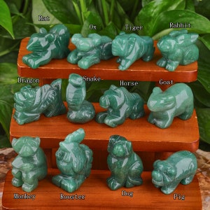 May include: A set of 12 green jade stone animal figurines representing the Chinese zodiac signs. The figurines are arranged in three rows on a wooden shelf. The signs are Rat, Ox, Tiger, Rabbit, Dragon, Snake, Horse, Goat, Monkey, Rooster, Dog, and Pig.