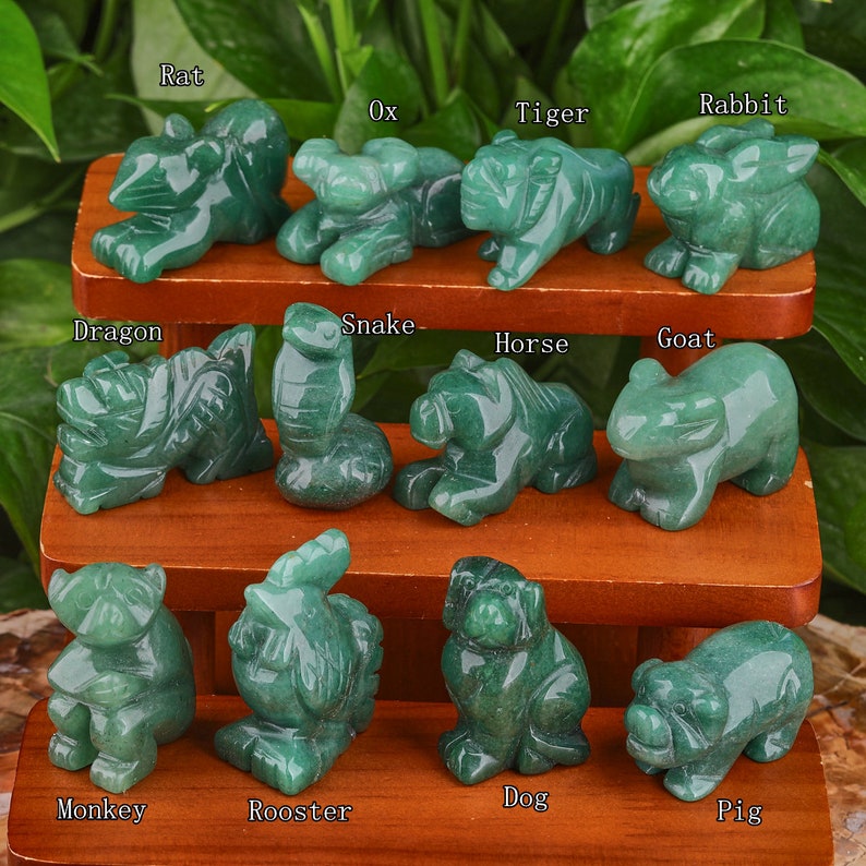 May include: A set of 12 green jade stone animal figurines representing the Chinese zodiac signs. The figurines are arranged in three rows on a wooden shelf. The signs are Rat, Ox, Tiger, Rabbit, Dragon, Snake, Horse, Goat, Monkey, Rooster, Dog, and Pig.