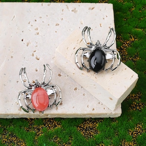 Handcrafted natural crystal spider featuring a polished gemstone body set in a finely crafted alloy spider frame. designed with natural stones creating a luxurious and artistic jewelry piece. The smooth gemstone surface and detailed spider legs give it a striking and elegant appearance. Perfect as a pendant necklace or brooch accessory symbolizing creativity, protection, and good fortune. Ideal for meditation energy healing, spiritual balance, fashion styling, gift giving, and decorative display