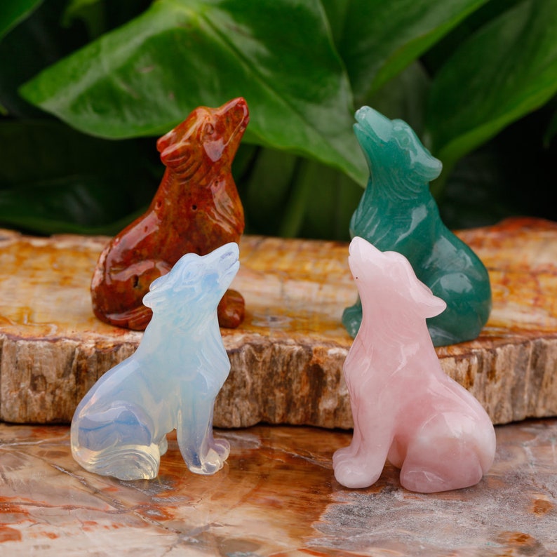 Puede incluir: Cuatro figuritas de lobo talladas en diferentes tipos de piedra. Los lobos est&aacute;n todos sentados con la cabeza echada hacia atr&aacute;s y la boca abierta. Las piedras son de color marr&oacute;n rojizo, azul claro, rosa claro y verde oscuro.