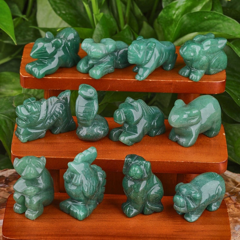 May include: A set of twelve green jade animal figurines, each representing a different animal of the Chinese zodiac. The figurines are arranged on a two-tiered wooden display stand.