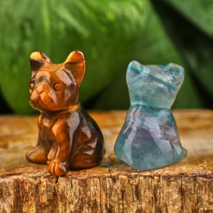 May include: Two small carved animal figurines. A brown and gold tiger eye stone figurine of a French bulldog sitting. A blue and green fluorite stone figurine of a cat sitting.
