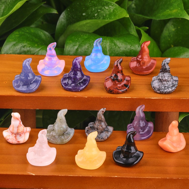 May include: A collection of 15 witch hat shaped crystal figurines in various colours and patterns. The hats are made of different types of crystals, including amethyst, rose quartz, and obsidian.