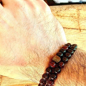 May include: A double-strand bracelet made of dark red and black beads with a small gold accent.
