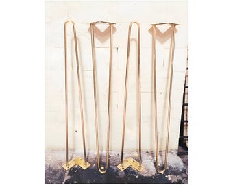 May include: Four gold metal hairpin legs for a table or other furniture. The legs are about 16 inches tall and have a simple, modern design.