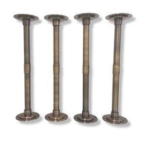 Puede incluir: Cuatro patas de mesa ajustables de latón antiguo con placas redondas. Cada pata está hecha de tubos de metal con un patrón decorativo.