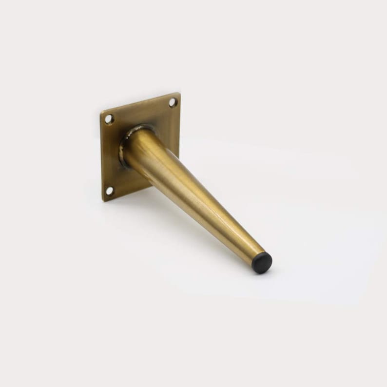 May include: A gold metal furniture leg with a square mounting plate and a black plastic tip.