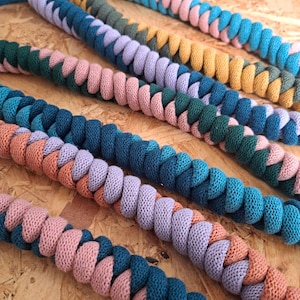 May include: Multiple lengths of thick, braided cord made from soft fabric. Each cord features a two-tone spiral pattern in various color combinations, including teal and pink, dark green and pink, blue and lavender, and mustard yellow and olive green.