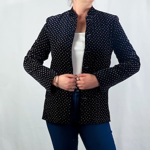 May include: A black velvet blazer with gold polka dots and a mandarin collar. The blazer has a button closure and is worn with blue jeans and black ankle boots.