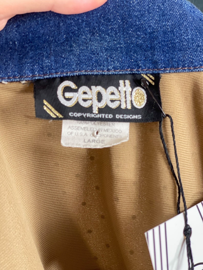 May include: A brown and tan shirt with a denim collar. The shirt has a label that reads "Gepetto Copyrighted Designs 100% Polyester Assembled in Mexico of U.S.A. Components Large".