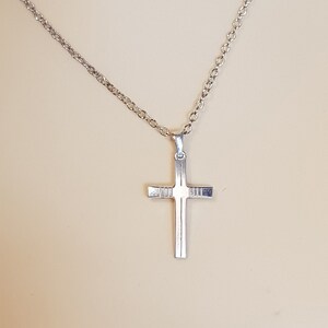 May include: A silver chain necklace with a silver cross pendant.