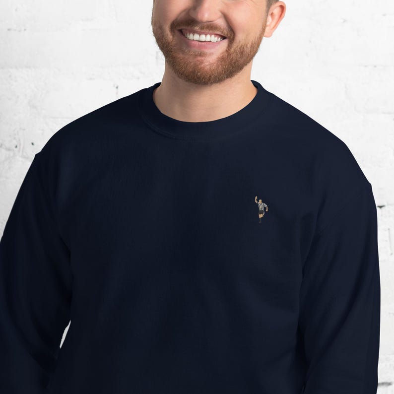 Pode incluir: Uma camisa de moletom azul marinho com uma pequena imagem bordada de uma pessoa em uniforme de &aacute;rbitro.