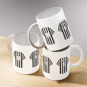 May include: Four white ceramic mugs with gray handles are stacked on a wooden surface. Each mug features a black and white striped jersey design with player names and numbers. The jerseys have the numbers 8, 9, and 14.