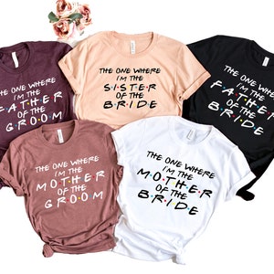 May include: Five t-shirts with the text "The One Where I'm The..." in a Friends-inspired font. The shirts are in different colors and feature the words "Father of the Groom", "Sister of the Bride", "Mother of the Groom", and "Mother of the Bride".