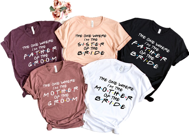 May include: Five t-shirts with the text "The One Where I'm The..." in a Friends-inspired font. The shirts are in different colors and feature the words "Father of the Groom", "Sister of the Bride", "Mother of the Groom", and "Mother of the Bride".