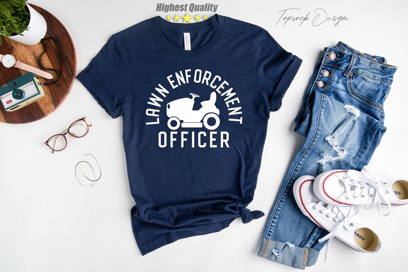 May include: A navy blue t-shirt with a white graphic of a lawnmower and the text "LAWN ENFORCEMENT OFFICER".