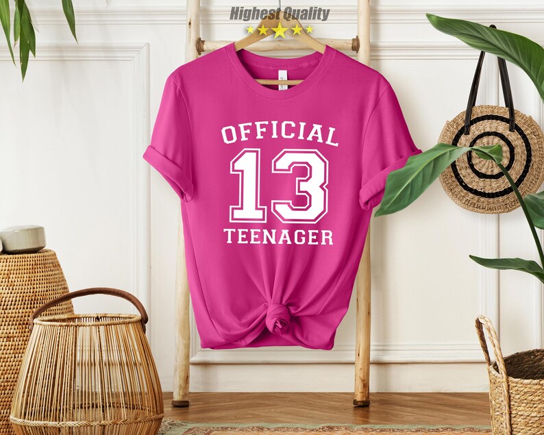 May include: Pink t-shirt with white text that says "Official 13 Teenager".