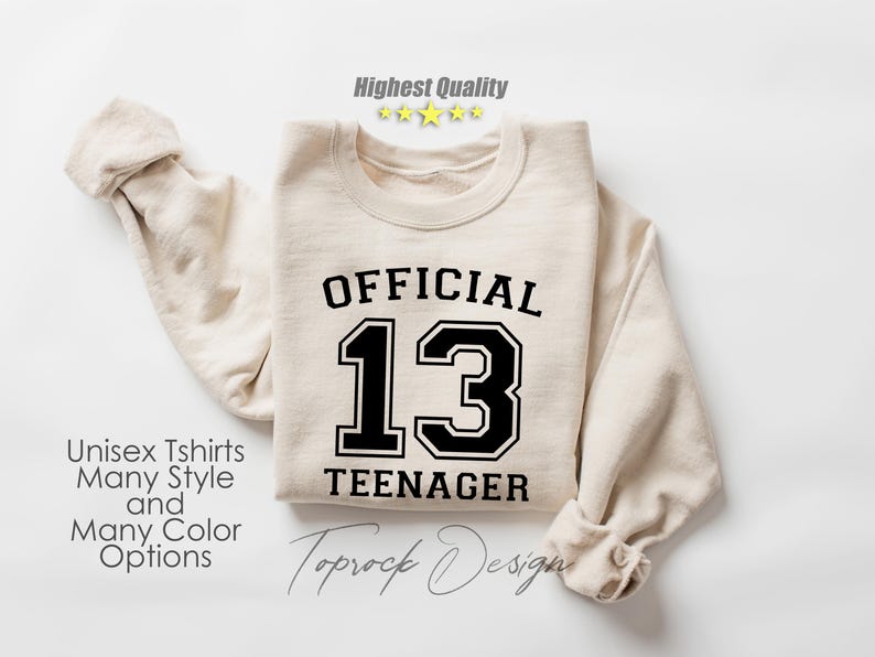 May include: A beige sweatshirt with black text that reads "OFFICIAL 13 TEENAGER".