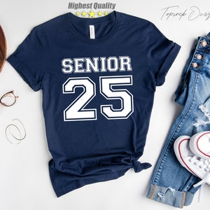 May include: A navy blue t-shirt with white text that says "Senior 25" in a varsity style font.