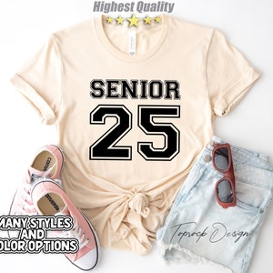 May include: A beige t-shirt with black text that says "Senior 25" in a varsity style font.