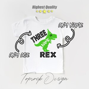 May include: White t-shirt with a green dinosaur wearing a party hat. The dinosaur says "NAME REX" and the text "THREE" is above the dinosaur. The text "ANY NAME" and "ANY AGE" are written on the shirt.