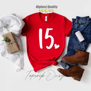 May include: Red t-shirt with the number 15 and a small white heart printed on the front. The shirt is on a white background.