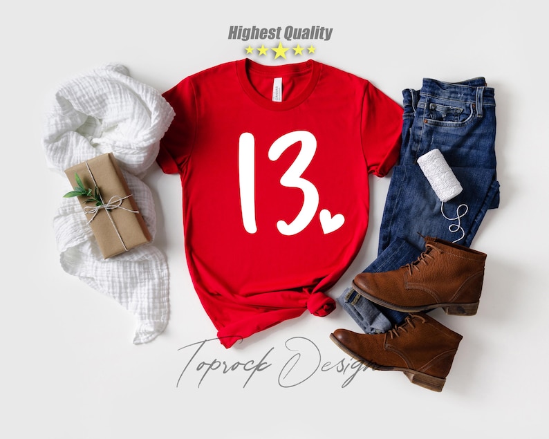 May include: Red t-shirt with white text that says "13" with a small heart next to it.  The shirt is on a white background.