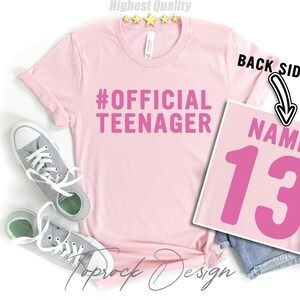 May include: Pink t-shirt with the text "#OFFICIAL TEENAGER" on the front and a pink number "13" with the word "NAME" above it on the back.