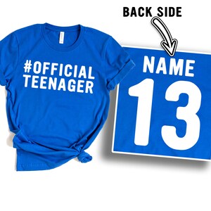 May include: Blue t-shirt with the text "#OFFICIAL TEENAGER" on the front and the number "13" on the back. The back also has the word "NAME" above the number.