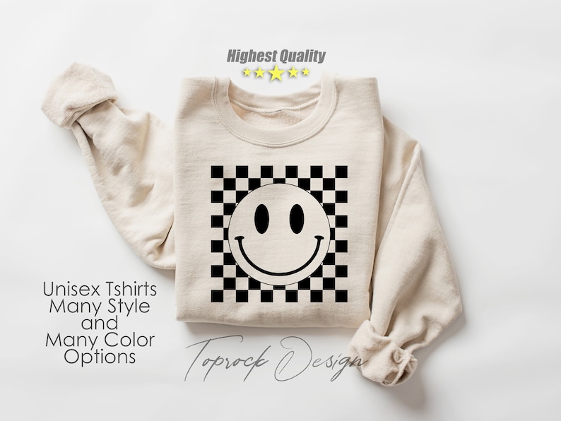 May include: A beige sweatshirt with a black and white checkered pattern and a black smiley face graphic. The text "Toprock Design" is printed on the bottom of the sweatshirt.