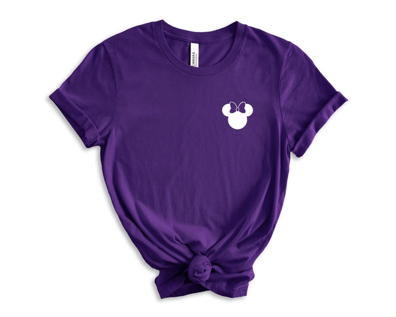 Puede incluir: Camiseta de manga corta de color morado con una silueta blanca de la cabeza de Minnie Mouse en el pecho izquierdo.