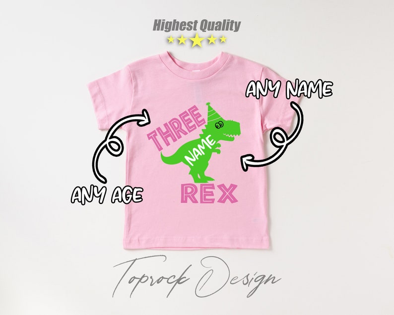May include: Pink t-shirt with a green dinosaur wearing a party hat. The dinosaur says "Three Name Rex".