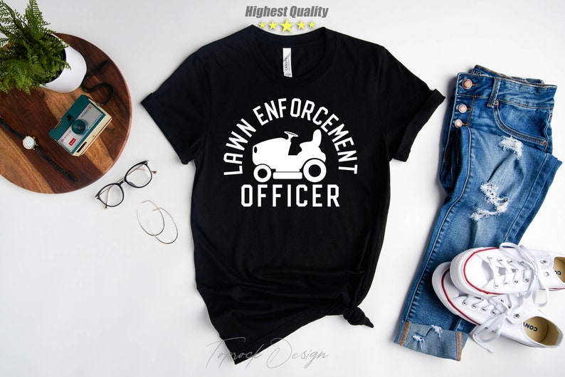 May include: Black t-shirt with a white graphic of a lawnmower and the text "Lawn Enforcement Officer".