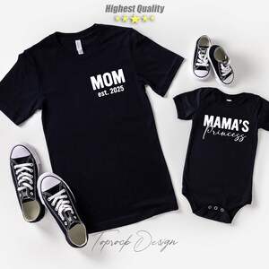 May include: Black t-shirt with "MOM est. 2025" text and a black baby onesie with "MAMA'S Princess" text. Two pairs of black and white canvas sneakers are also in the image. The image has a white background.