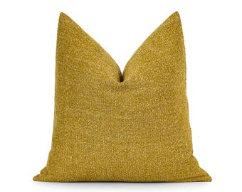 Puede incluir: Un cojín decorativo cuadrado de tela texturizada de color amarillo mostaza. El cojín tiene un aspecto suave y acogedor, perfecto para añadir un toque de color y confort a cualquier espacio habitable. El cojín mide aproximadamente 50 cm cuadrados.