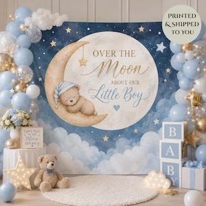 May include: A backdrop featuring a sleeping bear on a crescent moon with the text Over the Moon About Our Little Boy, surrounded by blue and white balloons, a teddy bear, light-up star, and stacked blocks spelling BABY on a white rug.