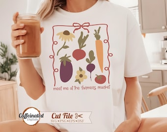 May include: White t-shirt with a colorful graphic of vegetables and flowers inside a red outline. The text "meet me at the farmers market" is below the graphic. The person is holding a glass jar with a brown liquid.