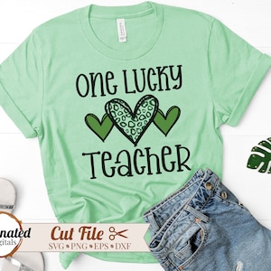 Może przedstawiać: Zielona koszulka z napisem "One Lucky Teacher" i wzorem serca w kolorze zielonym i leopardim.