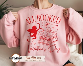 May include: A light pink sweatshirt with a red graphic design. The design includes the text "ALL BOOKED for Valentine's Day", a silhouette of Cupid, hearts, and a stack of books with humorous titles. The sweatshirt is a Valentine's Day theme.