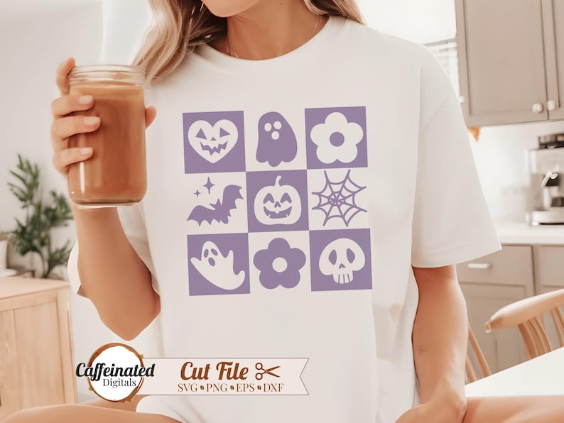 May include: A white t-shirt with a purple design of nine Halloween icons in a grid pattern. The icons include a ghost, a bat, a pumpkin, a spider web, a heart, a flower, and a skull.