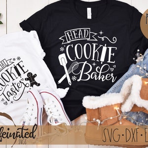 Pu&ograve; includere: Due magliette, una bianca e una nera, con testo a tema festivo. La maglietta bianca dice "Official Cookie Taster" e la maglietta nera dice "Head Cookie Baker". L'immagine include jeans, stivali e vegetazione festiva.
