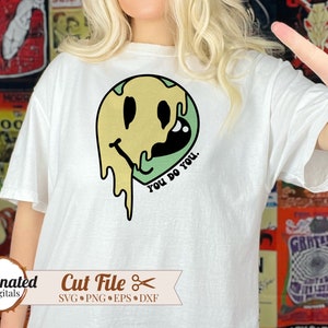 May include: A white t-shirt with a green, yellow, and black dripping smiley face graphic. The text "You do you." is written below the smiley face.